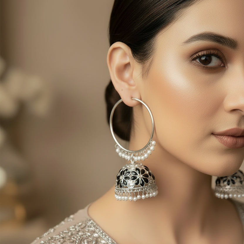 Pair of silver hoop earrings with jhumka designs on a black background
