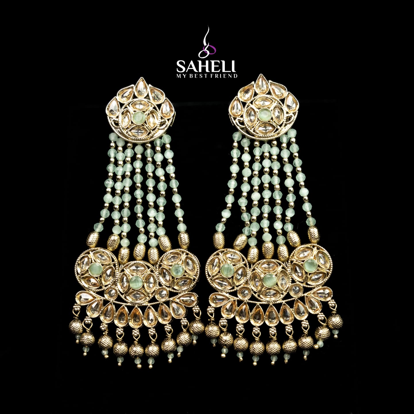 Ornate earrings with beads and gold accents on a black background, featuring the brand 'Saheli'.