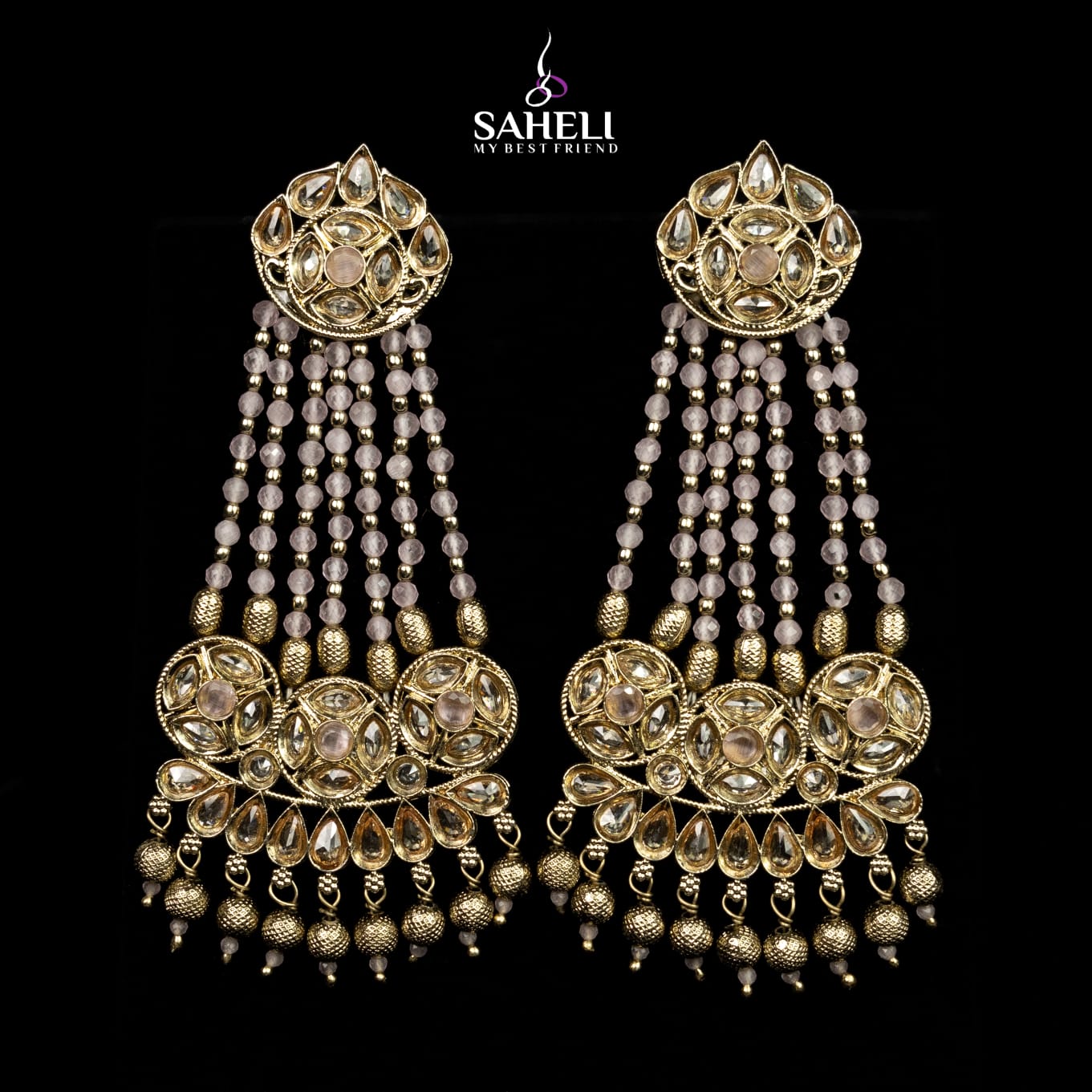 Gold and crystal earrings with 'Saheli' branding on a black background