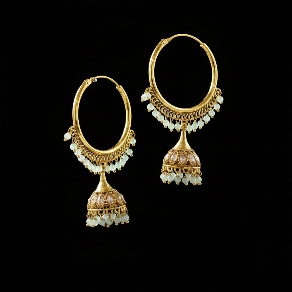 A pair of gold-toned traditional hoop earrings with dangling jhumka-style charms and small pale green bead drops, displayed on a dark gray stand against a light gray background.
