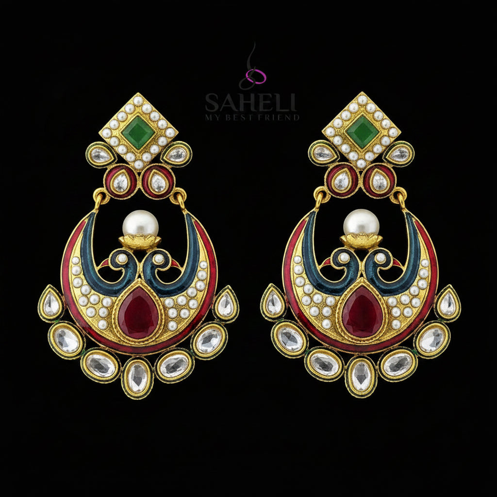 A pair of traditional Indian gold-plated earrings with red, green, and white enamel details, set against a dark reflective background with the brand logo 'SAHELI MY BEST FRIEND' at the top.