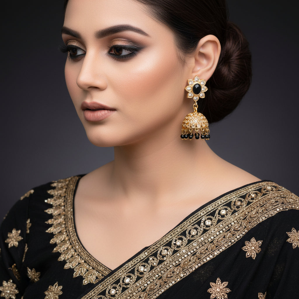 Ornate earrings with black and gold details on a dark background, featuring the brand 'Saheli'.