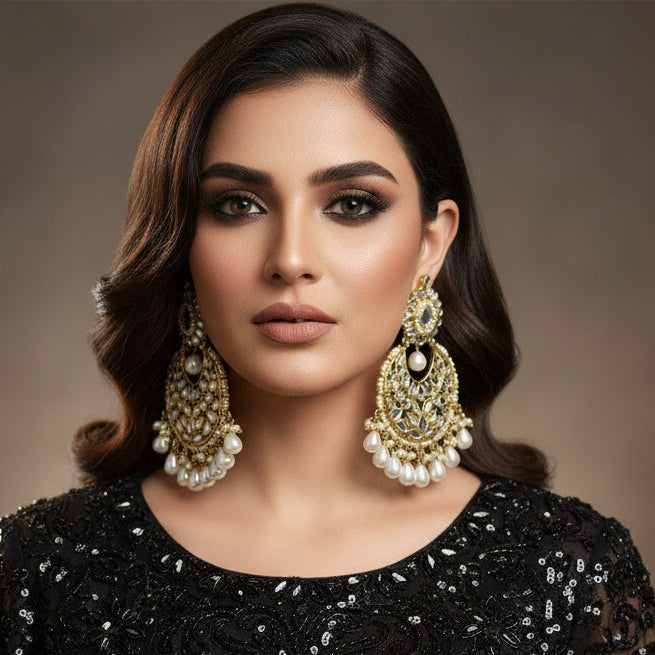 Pair of ornate earrings with pearls on a dark background