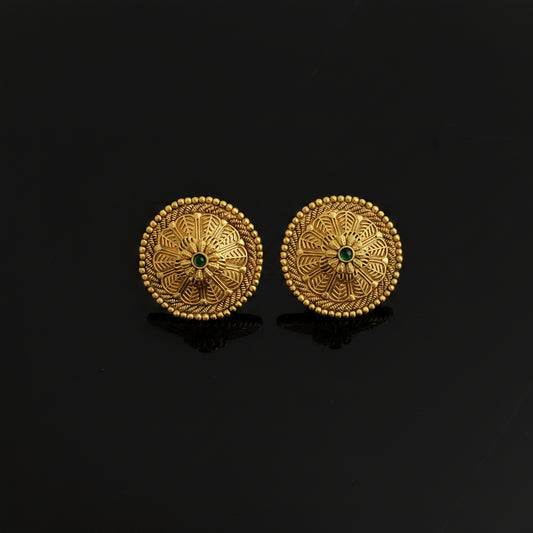 Pair of gold earrings with green gemstones on a black background