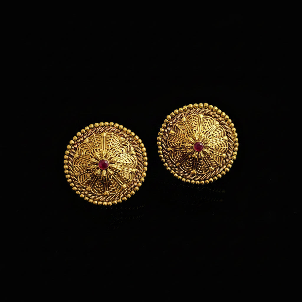 Pair of gold earrings with red gemstones on a black background