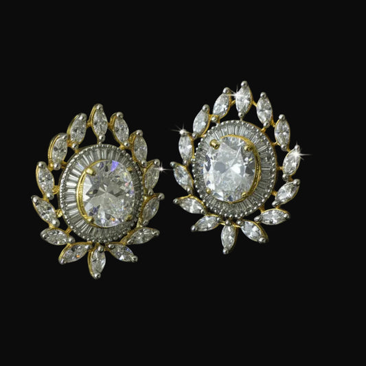 Pair of ornate earrings with clear gemstones on a black background