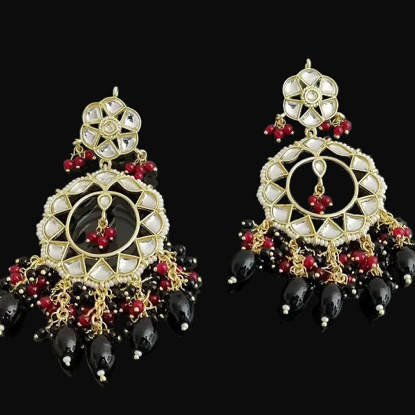 Pair of ornate earrings with black, red, and gold details on a dark background