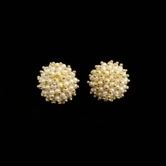 Pair of gold and pearl stud earrings on a black background
