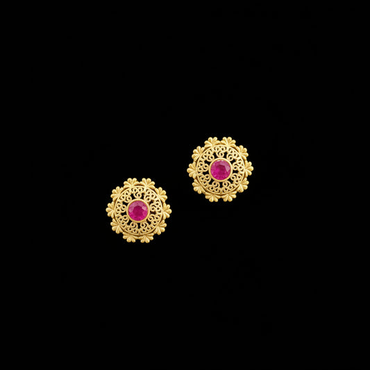 Gold earrings with red gemstones on a gray background