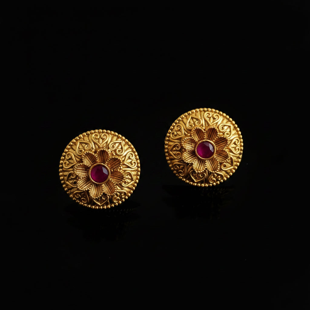 Pair of gold earrings with pink gemstones on a gray background