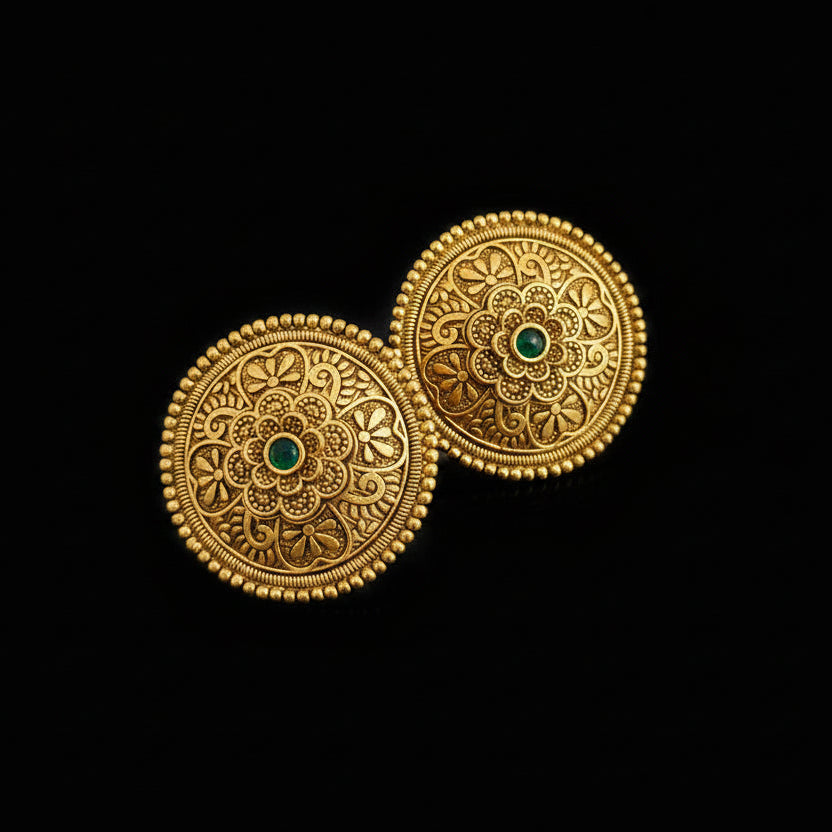 Pair of gold earrings with intricate designs on a dark background