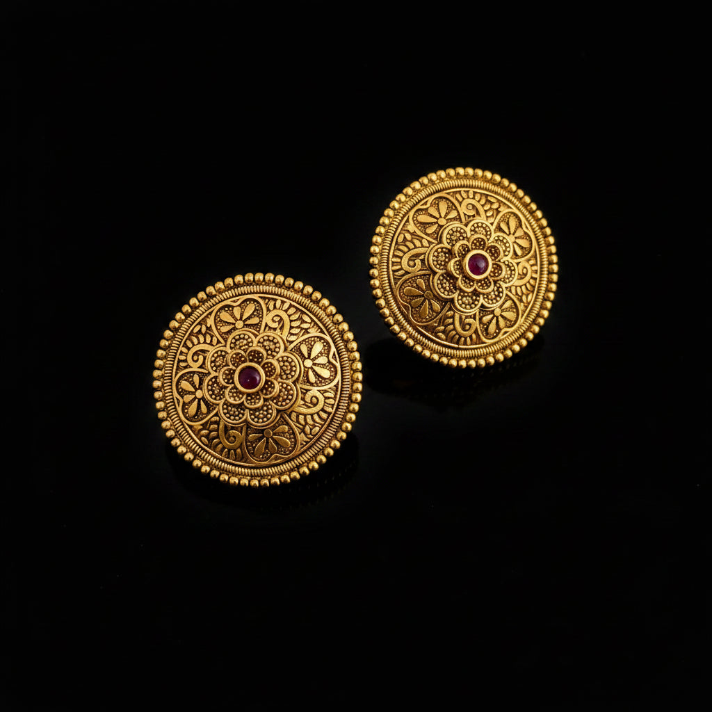 Pair of gold earrings with intricate designs on a dark background