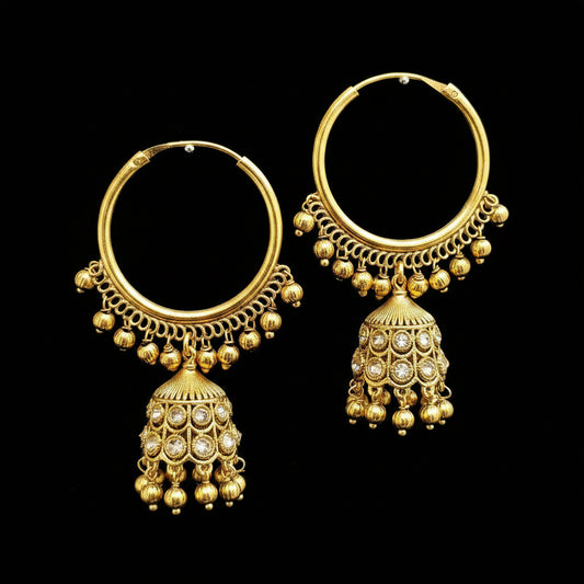 A pair of gold-toned traditional hoop earrings with dangling bell-shaped jhumka charms embellished with small clear stones, displayed on a gray jewelry stand.