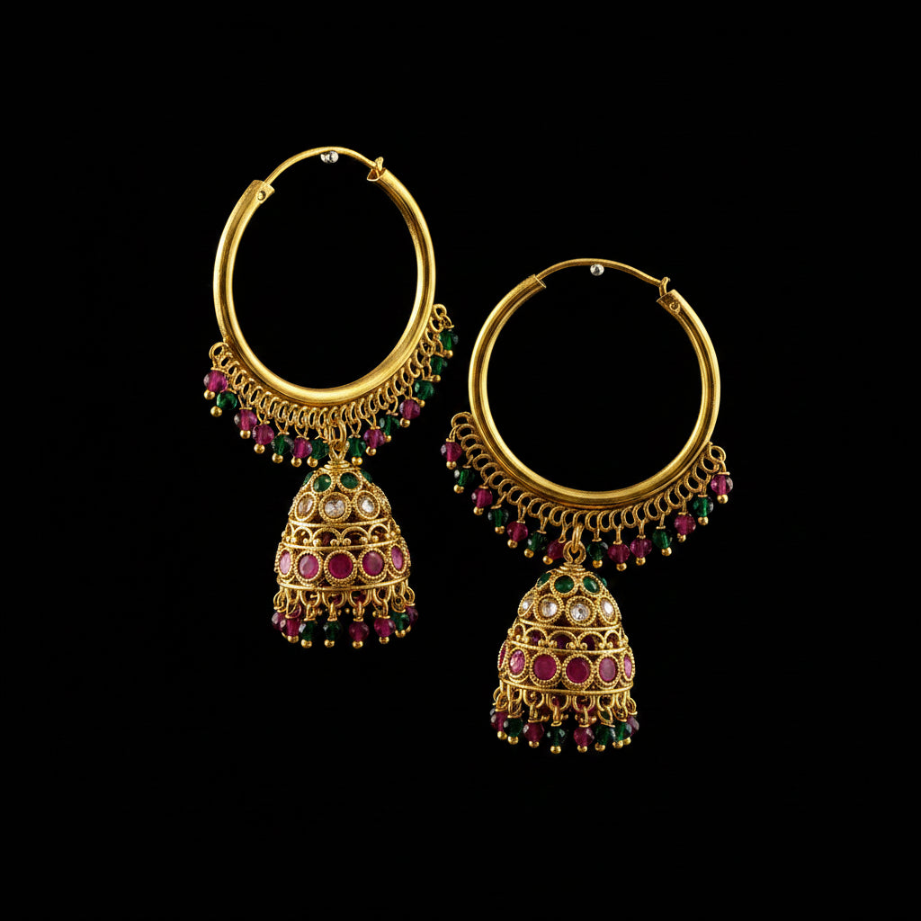 A pair of gold-toned traditional hoop earrings with dangling bell-shaped jhumka charms, decorated with pink and green stones, displayed on a gray stand.