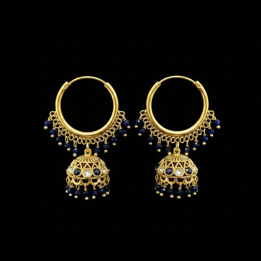 A pair of gold-toned hoop earrings with dangling filigree jhumka-style bells, dark blue bead drops, and small clear stones, displayed on a gray jewelry stand against a light gray background.