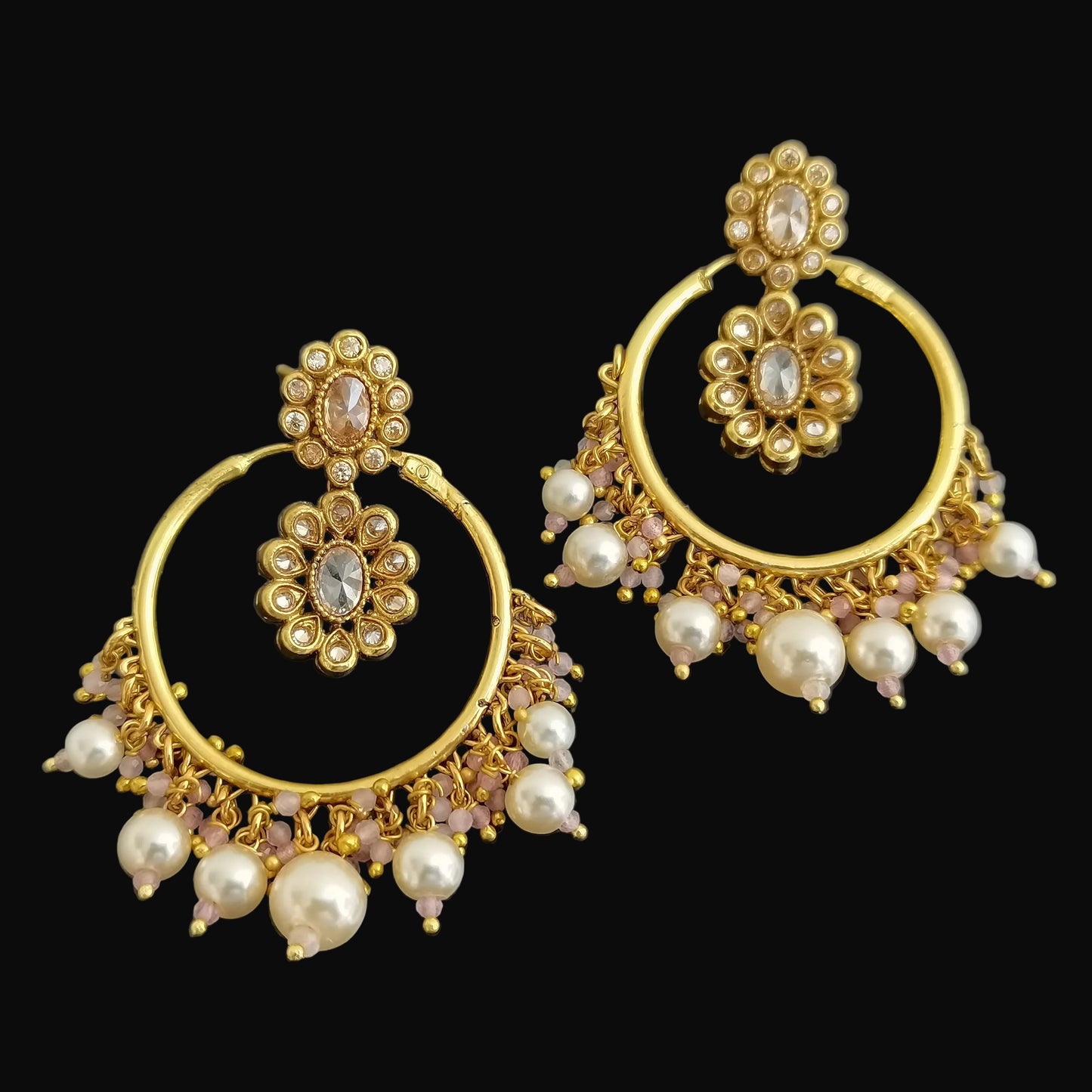 Gold and pearl earrings on a dark background