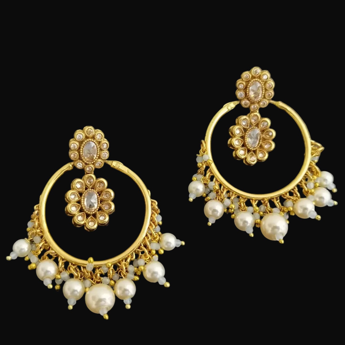 Gold earrings with pearl drops on a black background