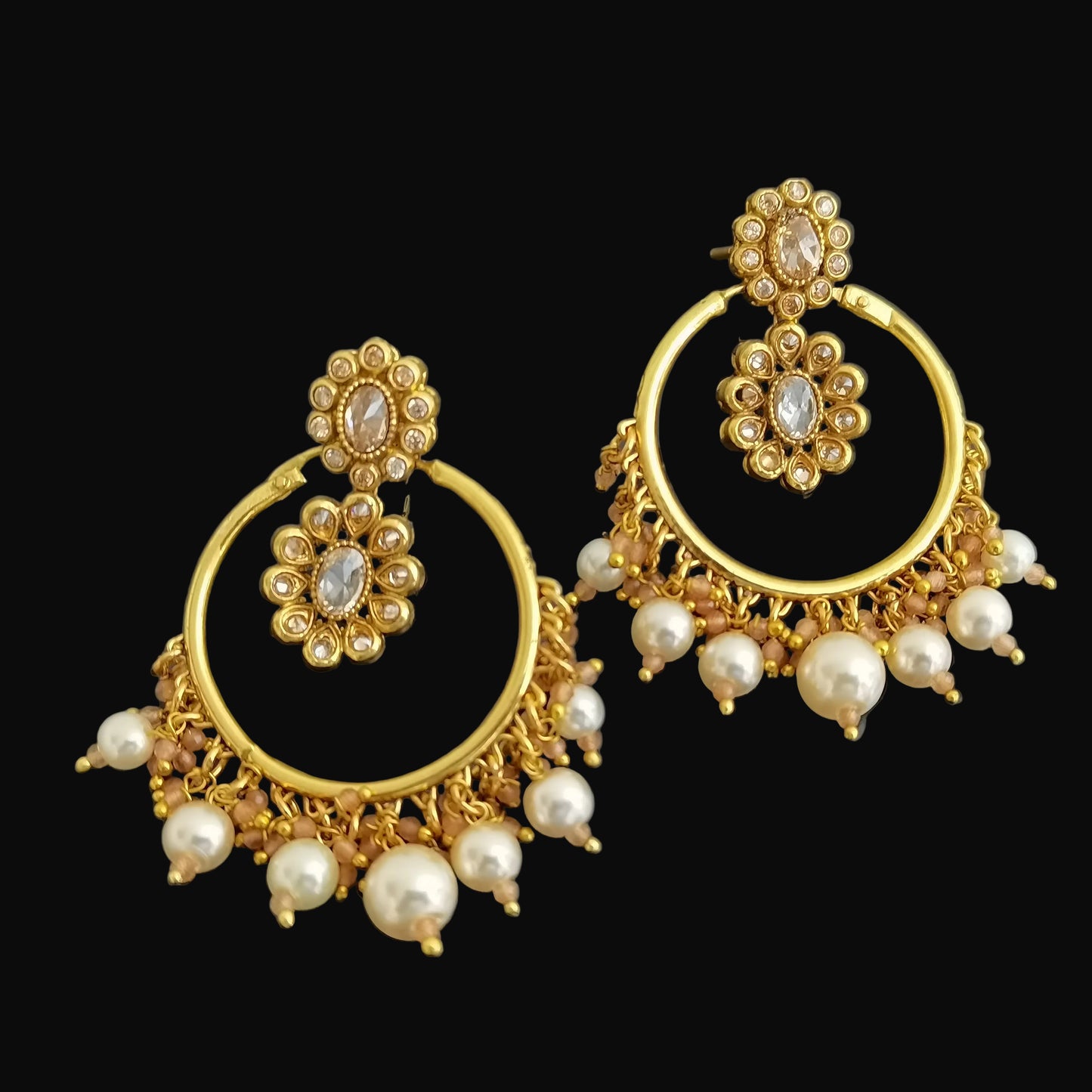 Gold and pearl earrings on a dark background