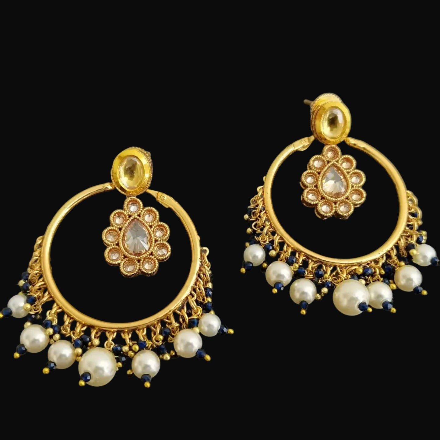 Pair of gold and pearl earrings on a black background