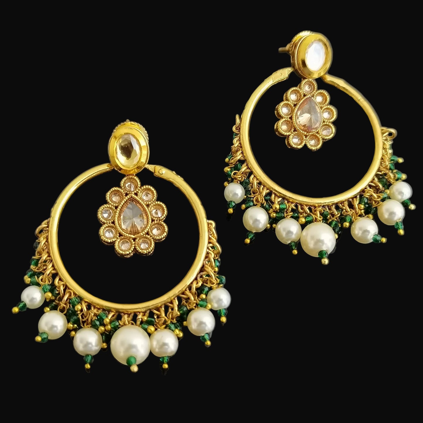 Gold earrings with pearls and green stones on a black background