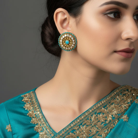 Pair of gold and turquoise earrings on a gray background with 'SAHELI' branding.