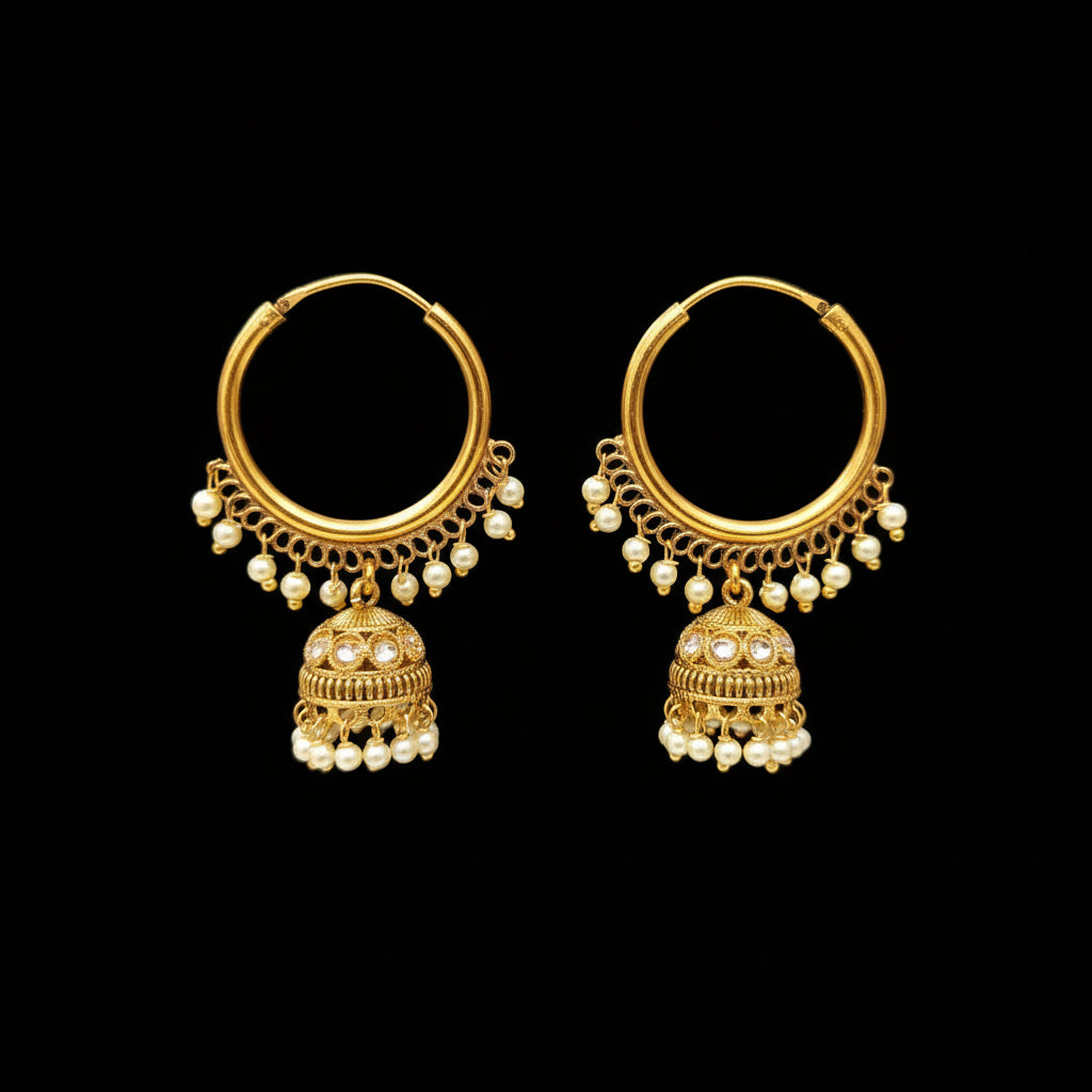Gold earrings with pearl drops on a black stand, branded 'SAHELI'.