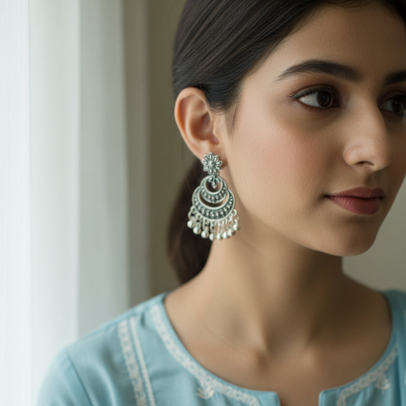 Pair of silver earrings with intricate designs on a dark background
