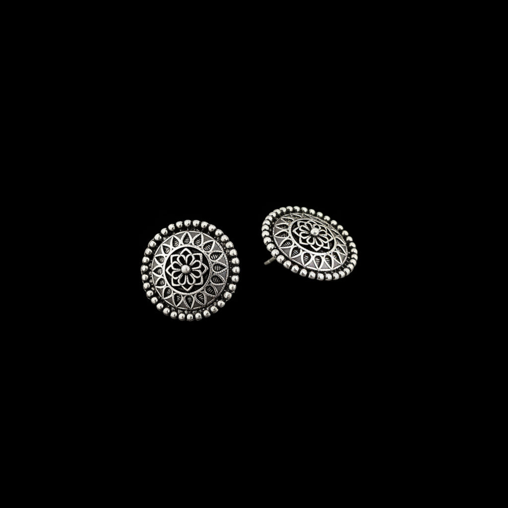 Pair of silver stud earrings with intricate designs on a gray background