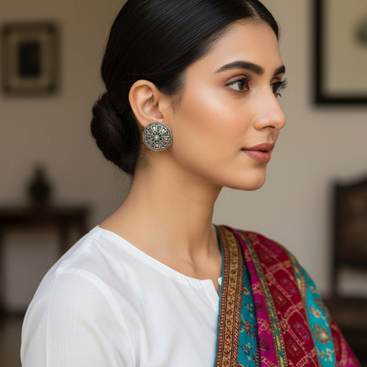 Pair of silver floral earrings on a dark gray background
