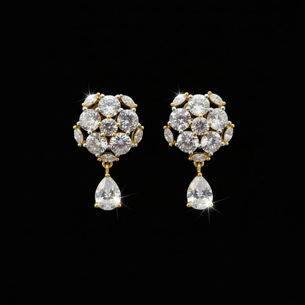 A pair of gold-toned statement earrings with clear gemstones, displayed on a black stand against a gray background with the brand name 'SAHELI MY BEST FRIEND' at the top.