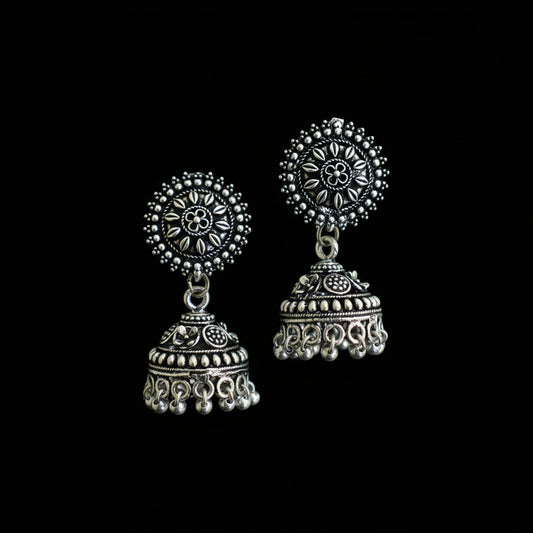Pair of silver earrings on a decorative peacock feather