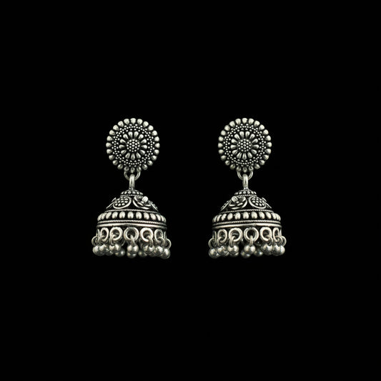 Silver earrings on a peacock feather with a gray background