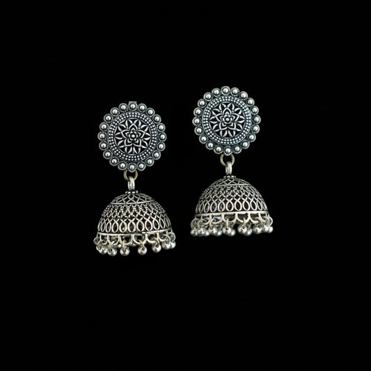 Pair of silver jhumka earrings on a decorative background