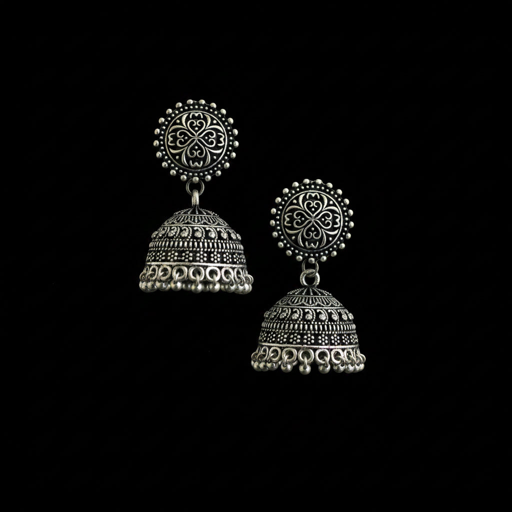 Pair of silver bell-shaped earrings on a decorative branch with a gray background
