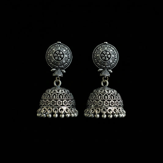 Ornate silver earrings on a peacock feather