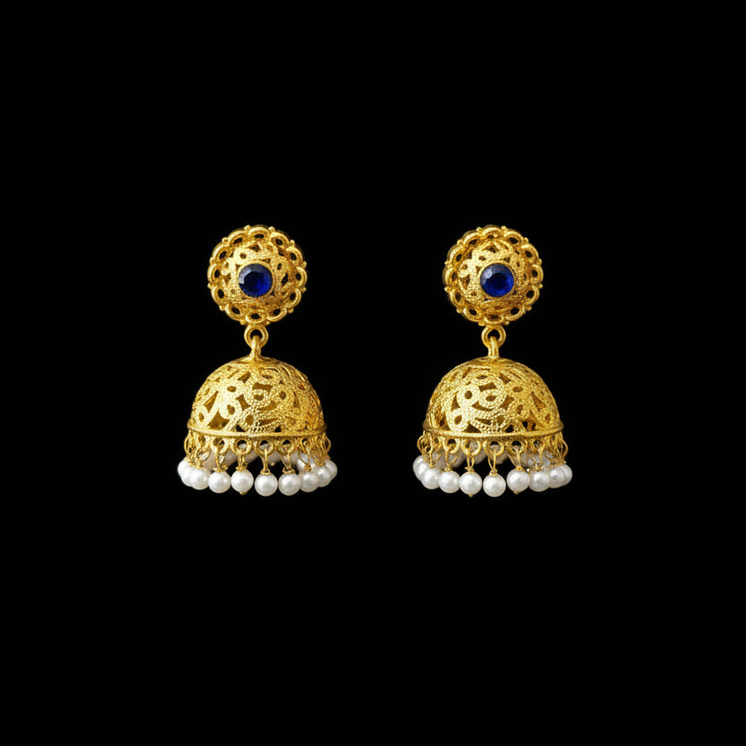 Gold earrings with blue stones and pearl accents on a gray stand, branded 'Saheili'.