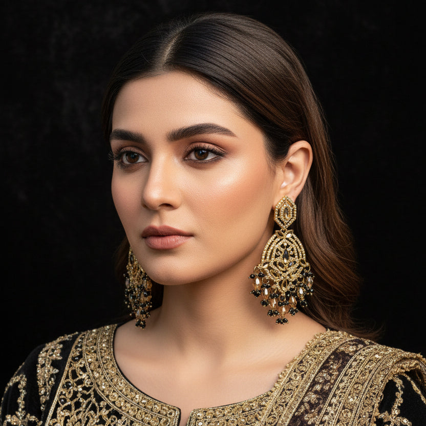 Ornate gold earrings on a stand with 'SAHELI' branding against a dark background
