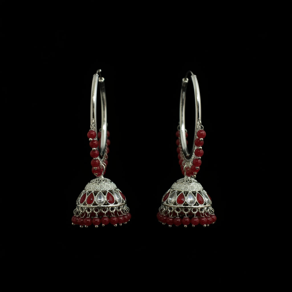 Pair of silver hoop earrings with red beads on a black background
