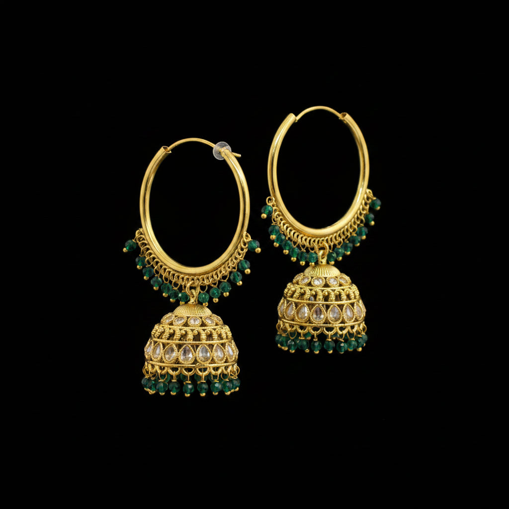 Gold hoop earrings with green gemstones on a gray stand.