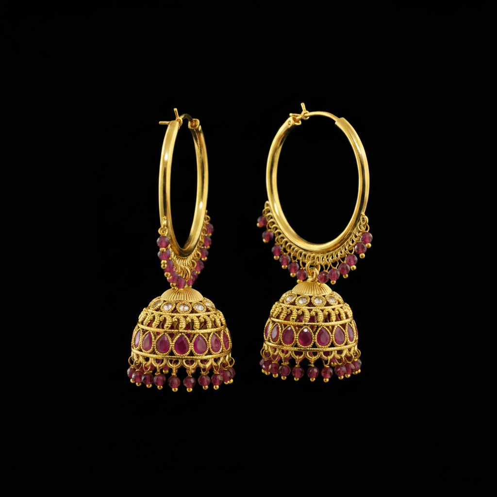 Gold hoop earrings with red gemstones on a gray stand