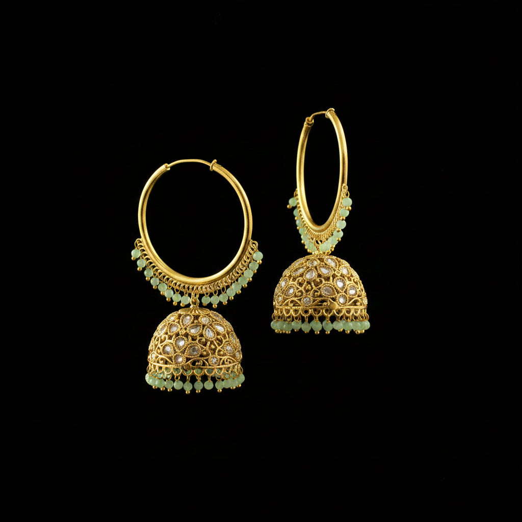 Gold hoop earrings with green beads on a black stand against a gray background