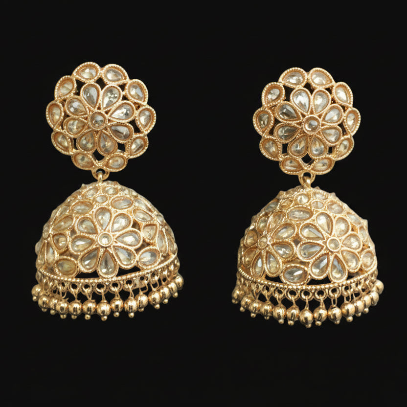 Pair of gold earrings on a gray stand with a neutral background