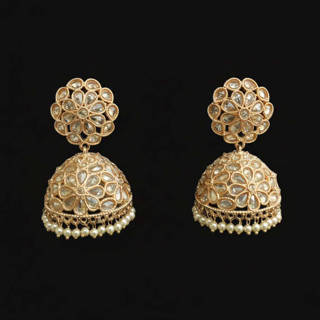 Gold and pearl earrings on black stands with a blurred background