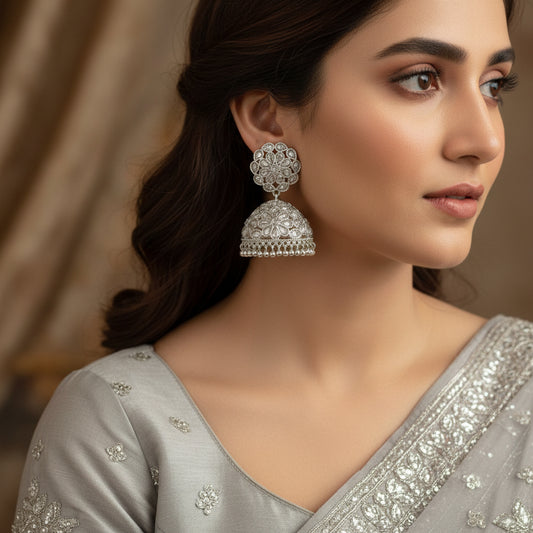 Pair of silver floral earrings on a gray stand with a blurred background