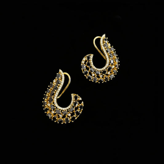 A pair of gold crescent-shaped earrings decorated with black and clear rhinestones, displayed on a dark reflective surface with the brand logo 'SAHELL MY BEST FRIEND' in the upper center.