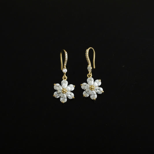 Pair of gold flower-shaped earrings on a black background