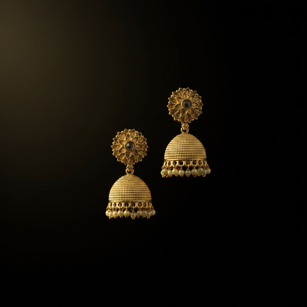 Gold jhumka earrings on a black stand with a gray background