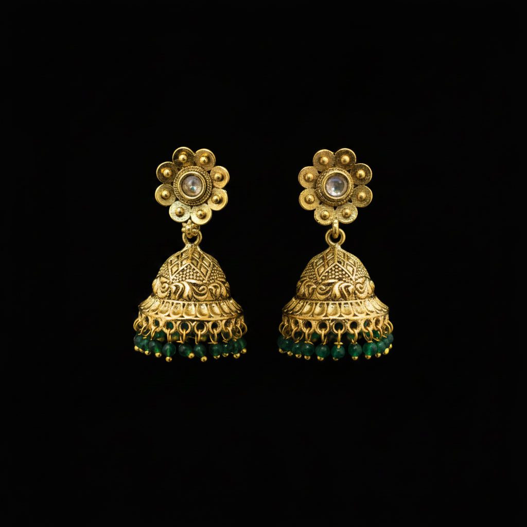 Gold and green floral earrings on a gray stand with a blurred background