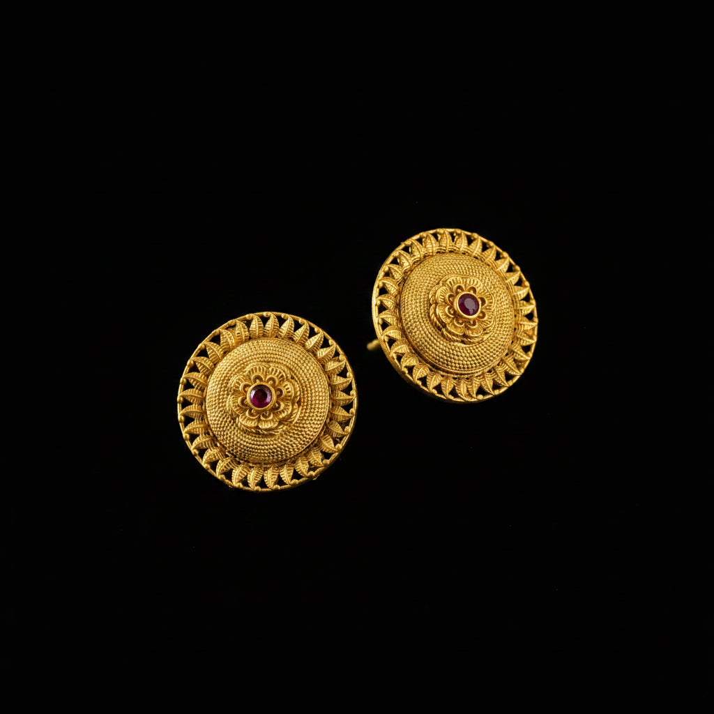 Pair of gold earrings with red gemstones on a black background