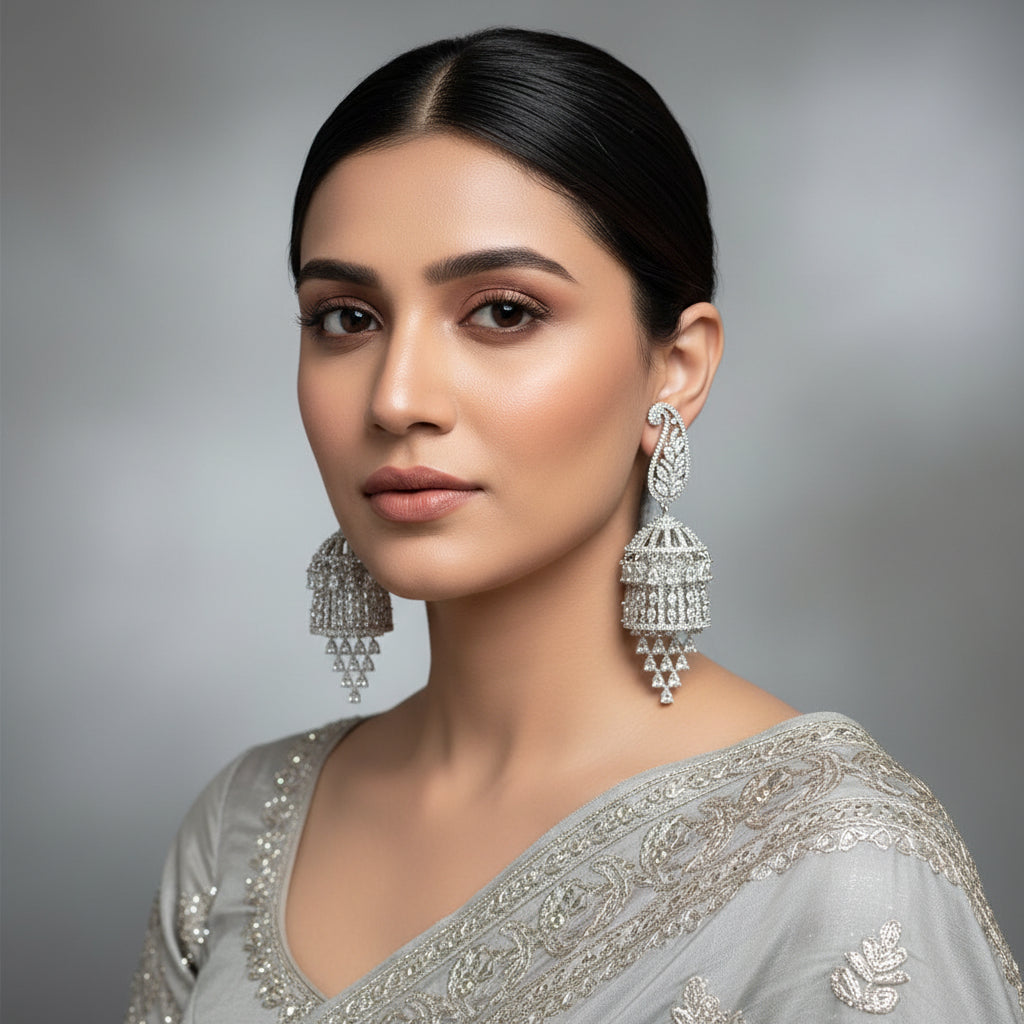 Silver earrings on a gray stand with 'Saheli' branding.